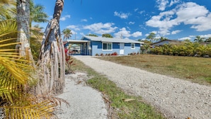A house with a gravel driveway leading to a blue building with a porch. - Beach Days & Backyard Nights! Fort Myers Retreat (Fort Myers)