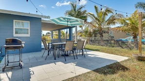 A patio with a grill, table, chairs, and a striped umbrella. - Beach Days & Backyard Nights! Fort Myers Retreat (Fort Myers)