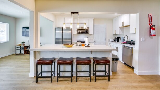 A modern kitchen with a central island, stainless steel appliances, and bar stools. - Beautiful 4-bedroom apartment with AC in peaceful San Diego (San Diego)