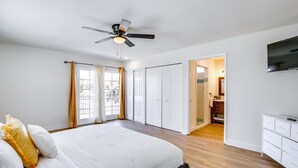 A bedroom with a bed, a ceiling fan, a bathroom with a mirror, and a TV on the wall. - Beautiful 4-bedroom apartment with AC in peaceful San Diego (San Diego)