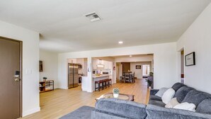 A modern living room with a grey sofa, a coffee table, and a kitchen in the background. - Beautiful 4-bedroom apartment with AC in peaceful San Diego (San Diego)
