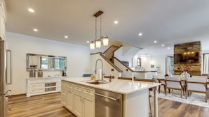 Una cocina moderna con una isla central, electrodomésticos de acero inoxidable y un amplio ventanal que proporciona luz natural.