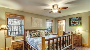 A bedroom with a wooden bed, a ceiling fan, and a window with a view of trees. - Hot Tub & Streamside Bliss! Topton Mtn Haven (Topton)