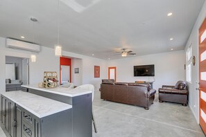 A spacious living area with a kitchen island, a brown leather sofa, and a ceiling fan. - 9 Mi to Joshua Tree! Desert Retreat w/ Fire Pit (Yucca Valley)