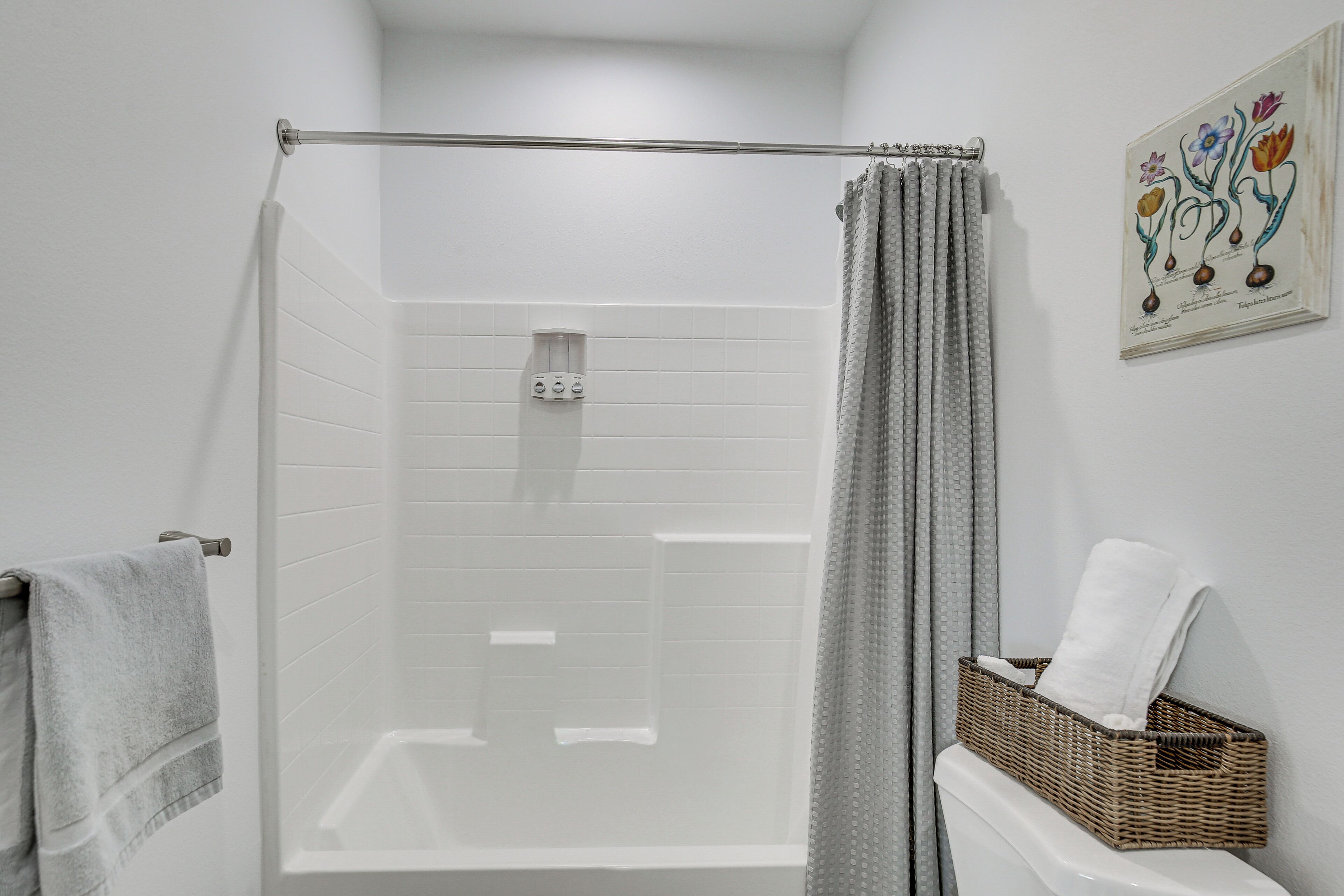 A shower area with a glass door, a towel rack, and a wicker basket on the wall.