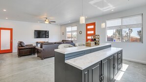 Eine moderne Küche mit einer großen Kochinsel, ein Essbereich mit einer Couch und ein Wohnzimmer mit Fernseher.