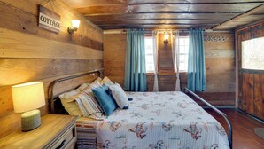 Una habitación de cabaña de madera con una cama, una mesita de noche, una lámpara y un letrero que dice "COTTAGE".
