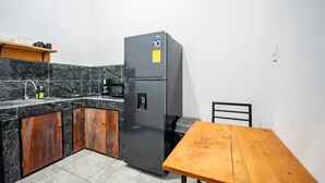 A compact kitchen with a refrigerator, a wooden table, and a sink. - Downtown Apartment by The Beach #5 (Sámara)