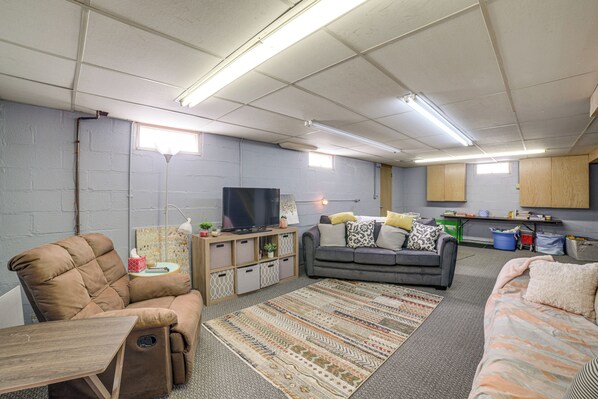 A compact living space with a sofa, a recliner, a television, and a kitchenette area. - Spacious & Peaceful Suburban Home in Lansing! (Lansing)