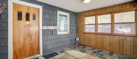 A hallway with a wooden door, a window with a curtain, and a patterned rug.
