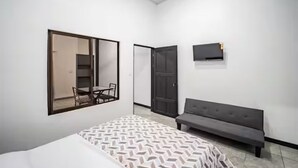 Ein Schlafzimmer mit einem Bett, einer Bank, einem Fernseher und einem Spiegel.