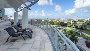 A balcony with chairs, a view of a cityscape, and a Ferris wheel in the distance. - The Vizcayne Vibe- Sauna, Pool and Sundeck (Miami)
