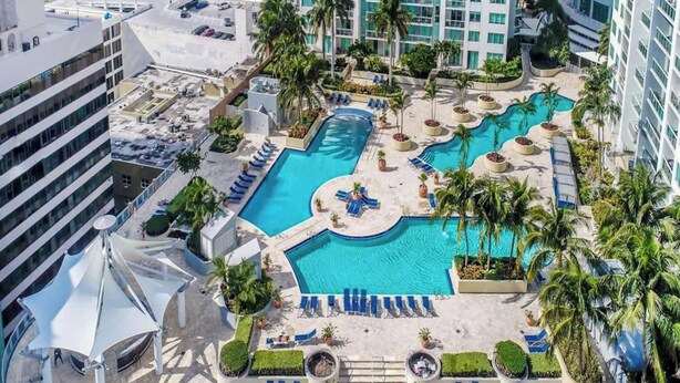 A rooftop pool area with multiple swimming pools, sun loungers, and palm trees. - The Vizcayne Vibe- Sauna, Pool and Sundeck (Miami)