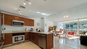 A modern kitchen with stainless steel appliances, wooden cabinets, and a central island. - Midtown Rouge- Condo with City Views, Pool & Gym (Miami)