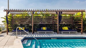 A pool area with a wooden pergola, lounge chairs, and a clear blue pool. - Midtown Rouge- Condo with City Views, Pool & Gym (Miami)
