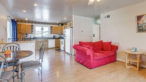 A modern kitchen with wooden cabinets, a dining area with a round table and chairs, a red sofa, and a ceiling fan. - Peaceful Getaway w/ Countryside Views in Upperco (Upperco)