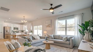 A modern living room with a sofa, chairs, a coffee table, and a view of the kitchen. - 4 Mi to Surf City Beaches! Family Coastal Retreat (Hampstead)