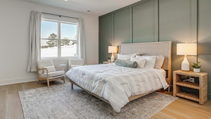 A bedroom with a bed, two bedside tables with lamps, a chair, a window with curtains, and a ceiling fan. - 4 Mi to Surf City Beaches! Family Coastal Retreat (Hampstead)