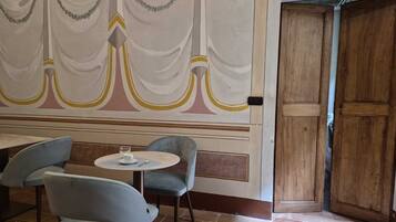 A room with a table and two chairs, a wooden door, and a wall with a decorative design.