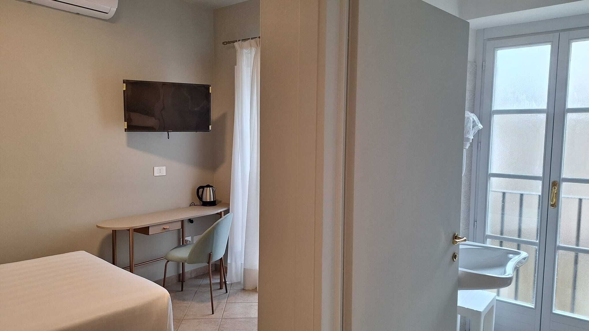 A room with a desk, chair, and a television mounted on the wall.