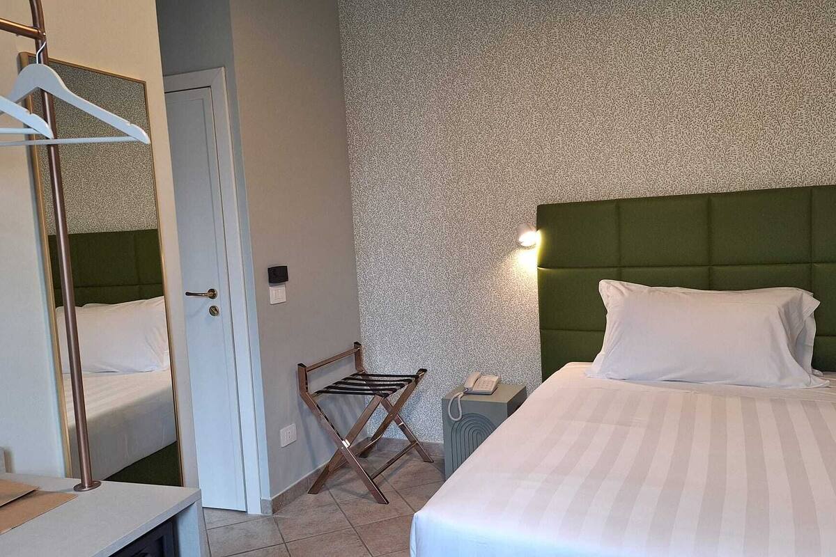 Una habitación de hotel con cama, una silla, armario y teléfono.