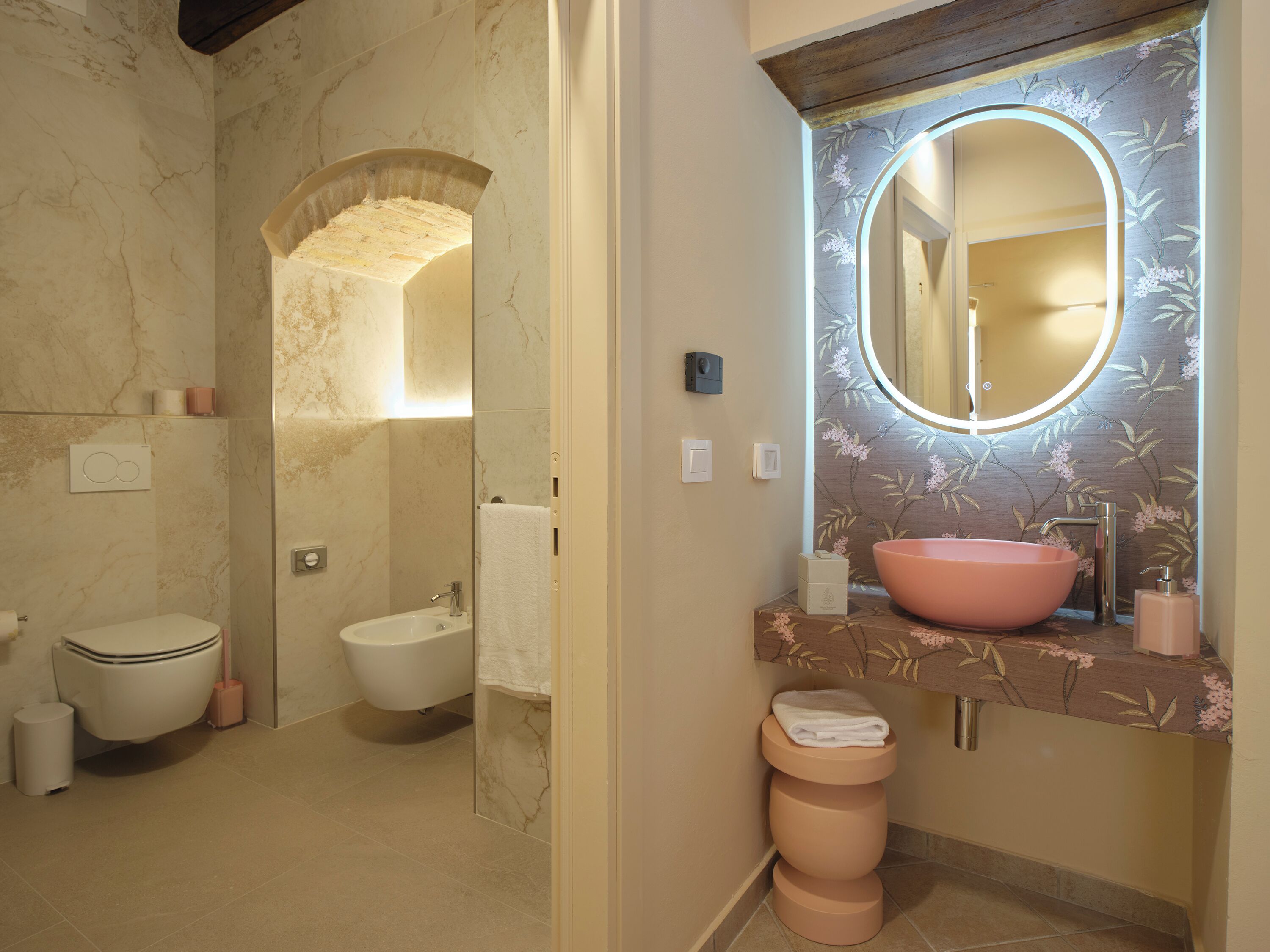 A bathroom with a toilet, bidet, and sink with a large mirror.