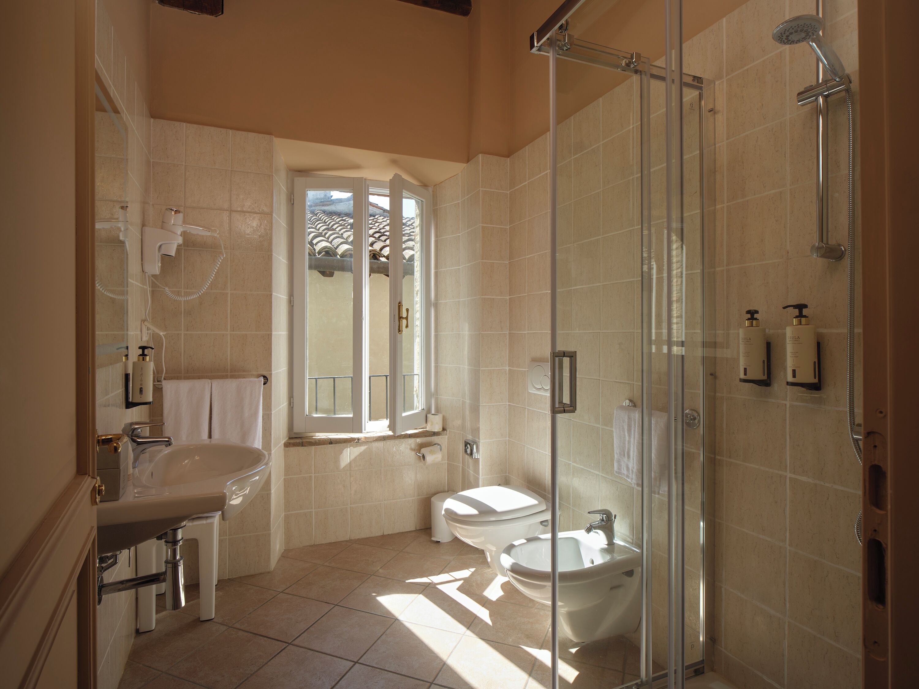 Un baño con ducha envuelta en vidrio, lavamanos, inodoro y bidé.