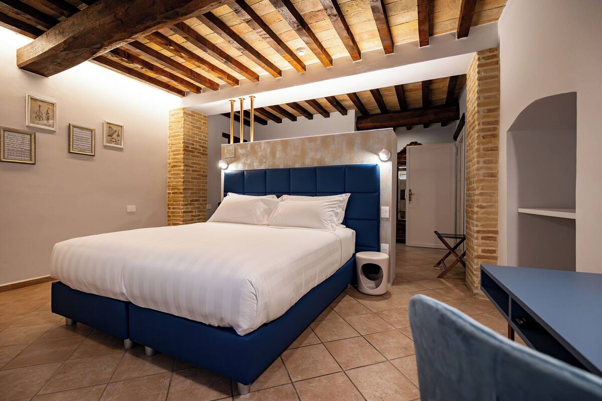 Un dormitorio con una cama grande, una mesita de noche pequeña, una silla, un inodoro y una zona de ducha.