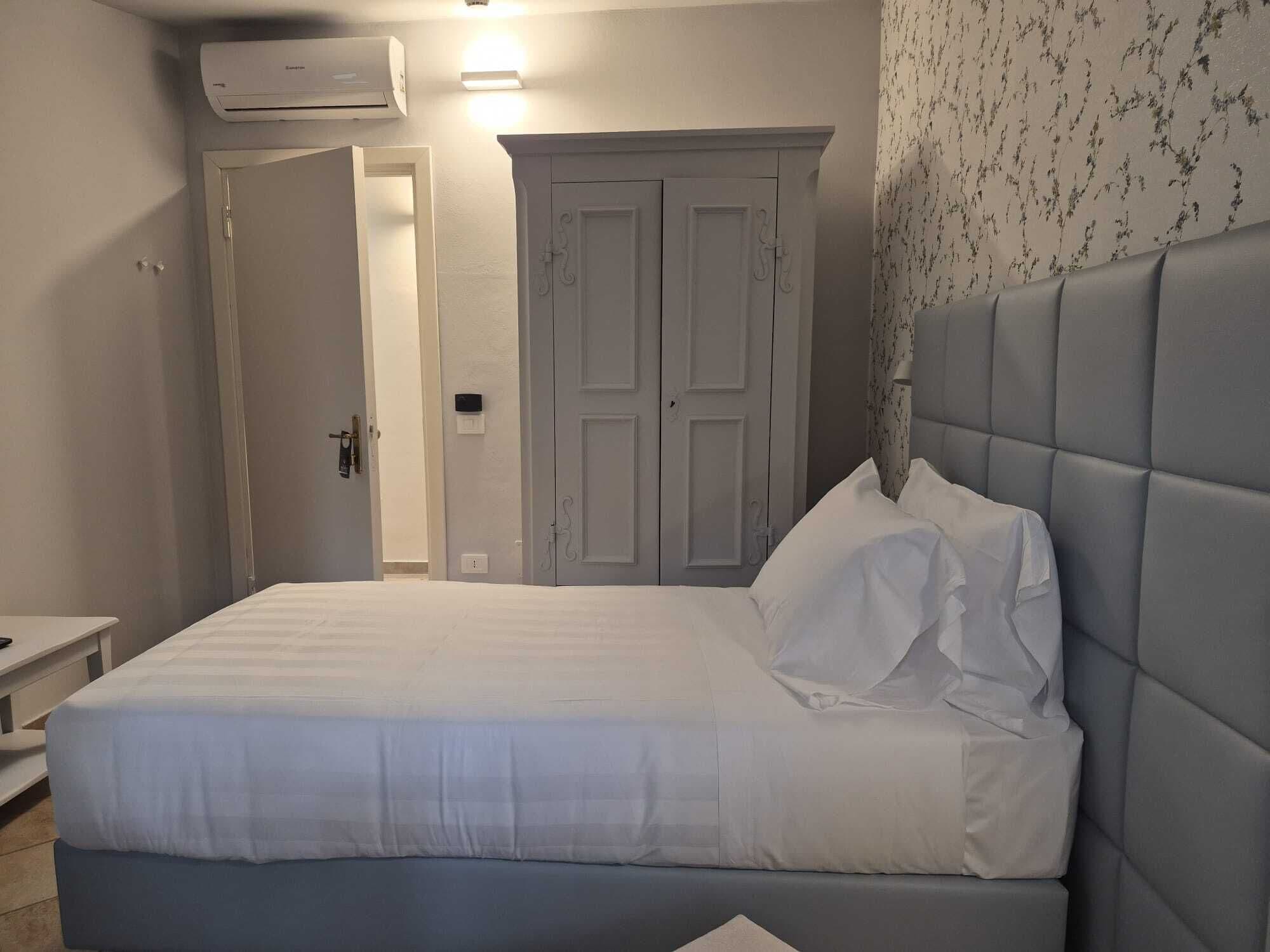 A bedroom with a bed, a wardrobe, and an air conditioning unit.