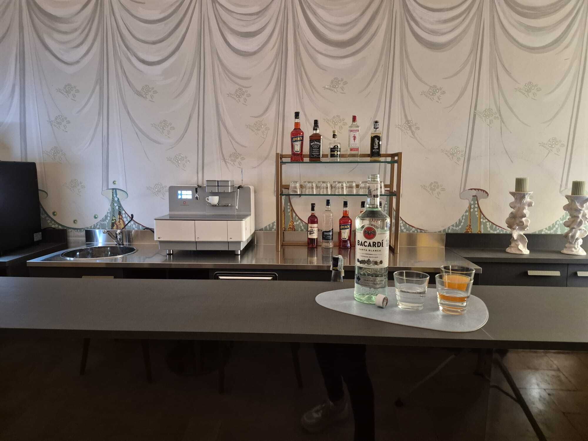 Ein Barbereich mit Minibar, einer Kaffeemaschine und einer Auswahl an Spirituosenflaschen.