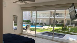 Une chambre moderne avec un grand lit, un ventilateur de plafond et une vue sur une piscine et un espace extérieur.