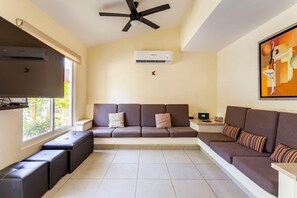 A living room with a sofa, a television, an air conditioner, and a ceiling fan. - Nueva Villa en Terrasol Diamante. (Acapulco de Juárez)
