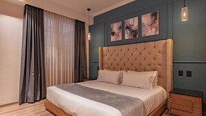 Een slaapkamer met een groot bed, een hoofdbord, een nachtkastje en een wandlamp.