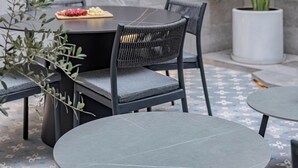 Een terras met een tafel, stoelen en een bloempot.