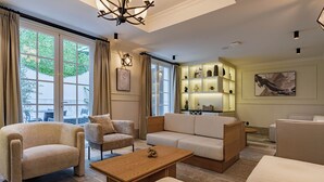 Een moderne woonkamer met een bank, fauteuils, een salontafel en een boekenkast.