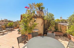 Une terrasse sur le toit, aménagée avec des espaces de détente en plein air, des plantes en pot et offrant une vue sur le paysage urbain.