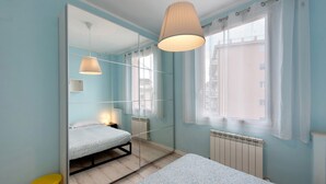 A bedroom with a bed, a mirror, a window, and a radiator.
