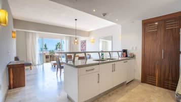 Una cocina moderna con una isla central, muebles blancos y una puerta grande de madera.