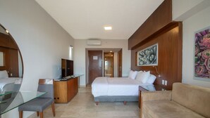 Een hotelkamer met een bed, een bureau met televisie, een glazen tafel, een bank en een schilderij aan de muur.