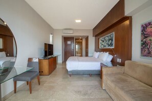 Een hotelkamer met een bed, een bureau met televisie, een glazen tafel, een bank en een schilderij aan de muur.