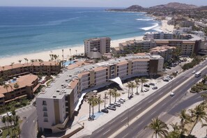A coastal hotel with multiple buildings, a beach, and a road.