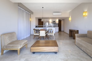 Un salon moderne avec un coin repas, une cuisine à l’arrière-plan, et un canapé et une table basse au premier plan.