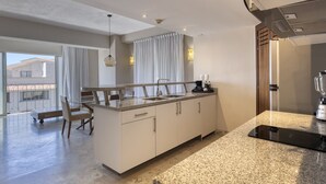 A modern kitchen with a granite countertop, white cabinetry, and a built-in coffee maker.