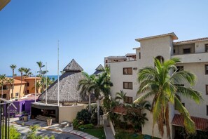 A resort with a pool, palm trees, and a building with a thatched roof. - Depto a 5 min del mar y el centro de San Jose 101 (San José del Cabo)