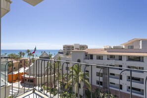 A balcony with a view of the sea, palm trees, and buildings with a tiled roof. - Depto a 5 min del mar y el centro de San Jose 101 (San José del Cabo)