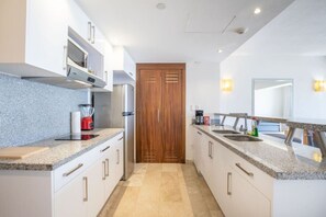 A modern kitchen with granite countertops, stainless steel appliances, and a wooden door.
