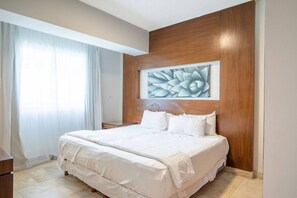 A bedroom with a large bed, wooden headboard, and a wall-mounted artwork.
