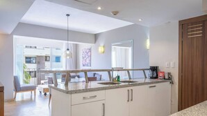 Una cocina moderna con encimeras de granito, un lavamanos empotrado y una zona de comedor con sofá y sillas.