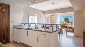 Une cuisine moderne dotée d’un grand îlot central, de meubles blancs et offrant une vue sur l’extérieur.