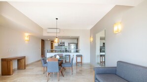 Un salon moderne avec un coin repas, un canapé et une cuisine en arrière-plan.